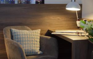a pillow on a chair next to a desk with a laptop at Lizz Hotel Munich in Munich