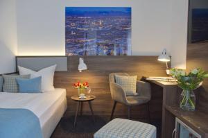 a hotel room with a bed, table and a painting on the wall at Lizz Hotel Munich in Munich