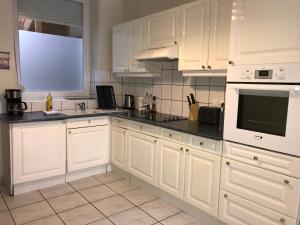 a kitchen with white cabinets and black counter tops at Sympathique logement en centre ville in Verdun