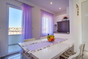 a dining room with a table and a large window at Apartmani Beatrice in Mali Lošinj