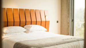 a bed with white sheets and pillows next to a window at Bossa Nova Beirut Hotel in Beirut