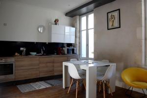 a kitchen with a white table and yellow chairs at Fouras Centre - Meublé Tourisme Classé 3 étoiles in Fouras +12 photos