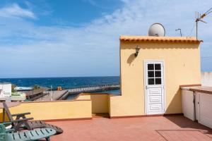 een geel gebouw met een witte deur en de oceaan bij Casita de playa in Puertito de Güímar