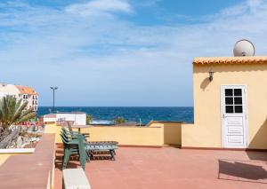 un patio con bancos y el océano en el fondo en Casita de playa, en Puertito de Güímar