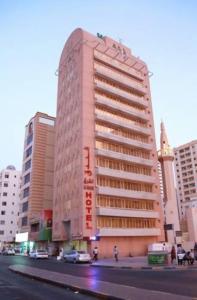 een hoog roze gebouw in een stadsstraat met gebouwen bij Al Sharq Hotel - BAITHANS in Sharjah
