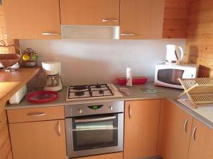 a kitchen with a stove and a microwave at Chalet des Grands Prés in Gercourt-et-Drillancourt
