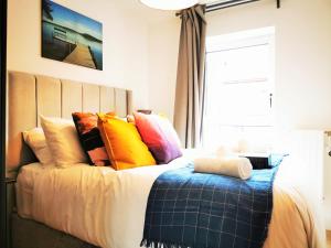 un letto con cuscini colorati sopra di Lovely Holiday Home in Birmingham City Center 3 Bedrooms House By HF Group a Birmingham
