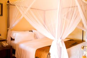 2 bedden met witte gordijnen in een slaapkamer bij Villa Kololo in Kampala