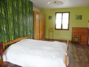 een slaapkamer met een wit bed en groene muren bij La guesnonniere in Quibou