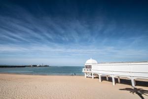 biały budynek na plaży nad wodą w obiekcie Apartamentos Las Musas de Cadiz w Kadyksie