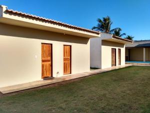 uma casa branca com portas de madeira e um quintal em Beach House em Flecheiras