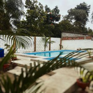 a swimming pool with a fence and trees at Hostal Surf Olón in Olón