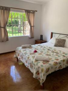 a bedroom with a bed with a flowered blanket and a window at Whynot Mauritius in Grand Gaube