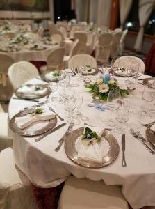 une grande table avec des tables blanches, des assiettes et des couverts dans l'établissement Platani Hotel, à Bolsena