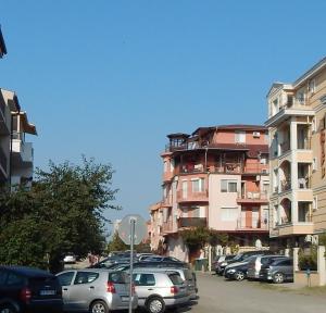 a parking lot with cars parked in front of a building at Dunav Apt.2 in Ravda