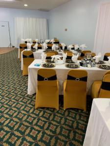 uma sala cheia de mesas e cadeiras com mesas brancas e cadeiras amarelas em Budget Inn & Suites - Talladega em Talladega