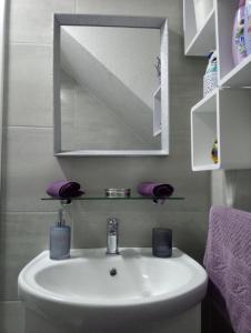 y baño con lavabo, espejo y toallas púrpuras. en Elly apartments Split en Split