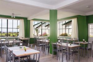 un restaurante con mesas, sillas y paredes verdes en IRUPÉ APART HOTEL en Federación