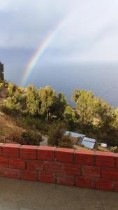 een regenboog over een stenen muur naast de oceaan bij Las Cabañas Lodge in Isla de Sol