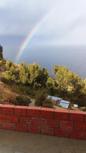 un arc-en-ciel au-dessus d'un mur de briques près de l'océan dans l'établissement Las Cabañas Lodge, à Isla de Sol