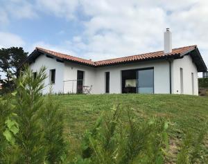 een wit huis bovenop een grasheuvel bij Villa avec piscine privée, vue sur mer et plage à pied 800m in Saint-Jean-de-Luz