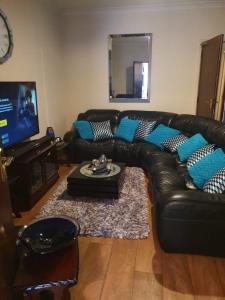 a living room with a black leather couch with blue pillows at Chaps Guesthouse Southampton in Southampton