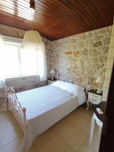 a bedroom with a white bed and a stone wall at Ktima Nafsika - First-floor luxury apartment in majestic estate in Rozaíika