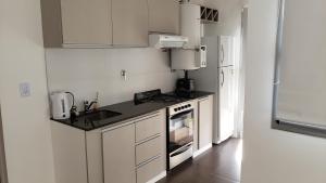 La cuisine est équipée d'un évier, d'une cuisinière et d'un réfrigérateur. dans l'établissement Tu lugar en Villa, à Villa Constitución