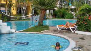 a girl in a swimming pool with a woman sitting in a chair at Villas Privadas en Palma Real in El Corazón