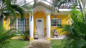 a yellow house with a white door and palm trees at Villas Privadas en Palma Real in El Corazón