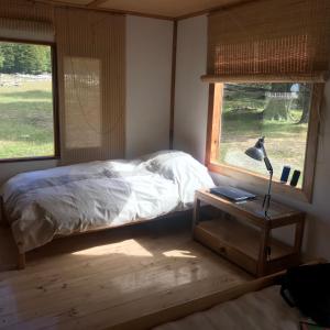 a bedroom with a bed and a lamp on a table at Cabaña Lago Largo in Coihaique