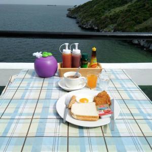 a table with a plate of breakfast food on a balcony at Ocean View Resort - Koh Sichang in Ko Si Chang