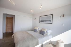 a white bedroom with a large bed with blue pillows at Pichilemu Surf Hotel in Pichilemu