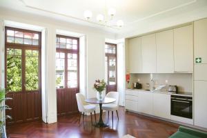una cucina con mobili bianchi, tavolo e sedie di Trindade Premium Apartments a Porto