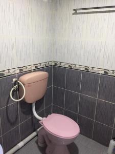 a pink toilet in a bathroom with black tiles at AMIMAS HOMESTAY in Kampong Telok