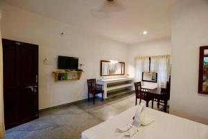 a room with a bed and a dining room with a table at Alice Paradise by Moonrakers in Mahabalipuram