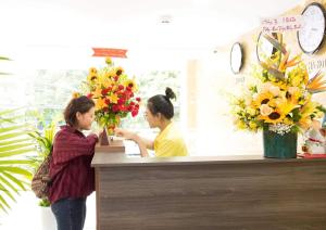 dos mujeres parados en un mostrador en una floristería en DORADO HOTEL, en Nha Trang