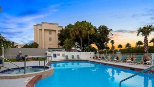 a swimming pool with chairs and a building at Best Western Ocala Park Centre in Ocala