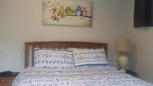 1 cama con 2 almohadas y una foto en la pared en Edgehill - semi self-contained eco friendly home, en Tauranga