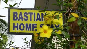 a sign that says bastacist home and a yellow flower at Bastian Homestay in Cochin