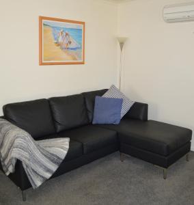 a black leather couch in a living room with a painting at Waterfall Cottage in Rosebud
