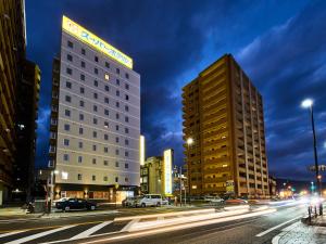 eine Stadt mit zwei hohen Gebäuden und Autos auf einer Straße in der Unterkunft Super Hotel Mihara Ekimae in Mihara