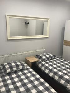 two beds in a room with a mirror on the wall at Piwnica in Miechów