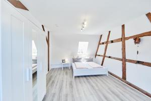 1 dormitorio blanco con 1 cama y suelo de madera en Wunderschöne Maisonette-Wohnung für bis zu 10 Personen, en Ettenheim