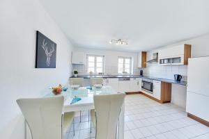 a white kitchen with a table and chairs in it at Wunderschöne Maisonette-Wohnung für bis zu 10 Personen in Ettenheim