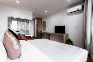 um quarto com uma grande cama branca e uma televisão em แจสเปอร์โฮเทล Jasper Hotel em Khon Kaen