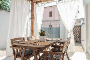 a wooden table and chairs on a balcony with white curtains at Casa Clementa in Pula