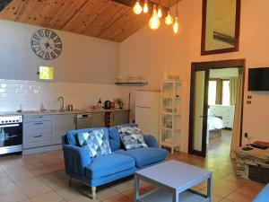 a living room with a blue couch and a kitchen at Hameau de Montcabirol - Pyrénées in Mirepoix