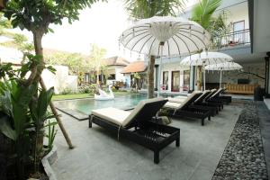 a pool with chairs and umbrellas next to a building at Surf Lodge Canggu in Canggu
