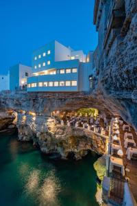 un restaurant sur une falaise à côté de l'eau la nuit dans l'établissement Hotel Grotta Palazzese, à Polignano a Mare